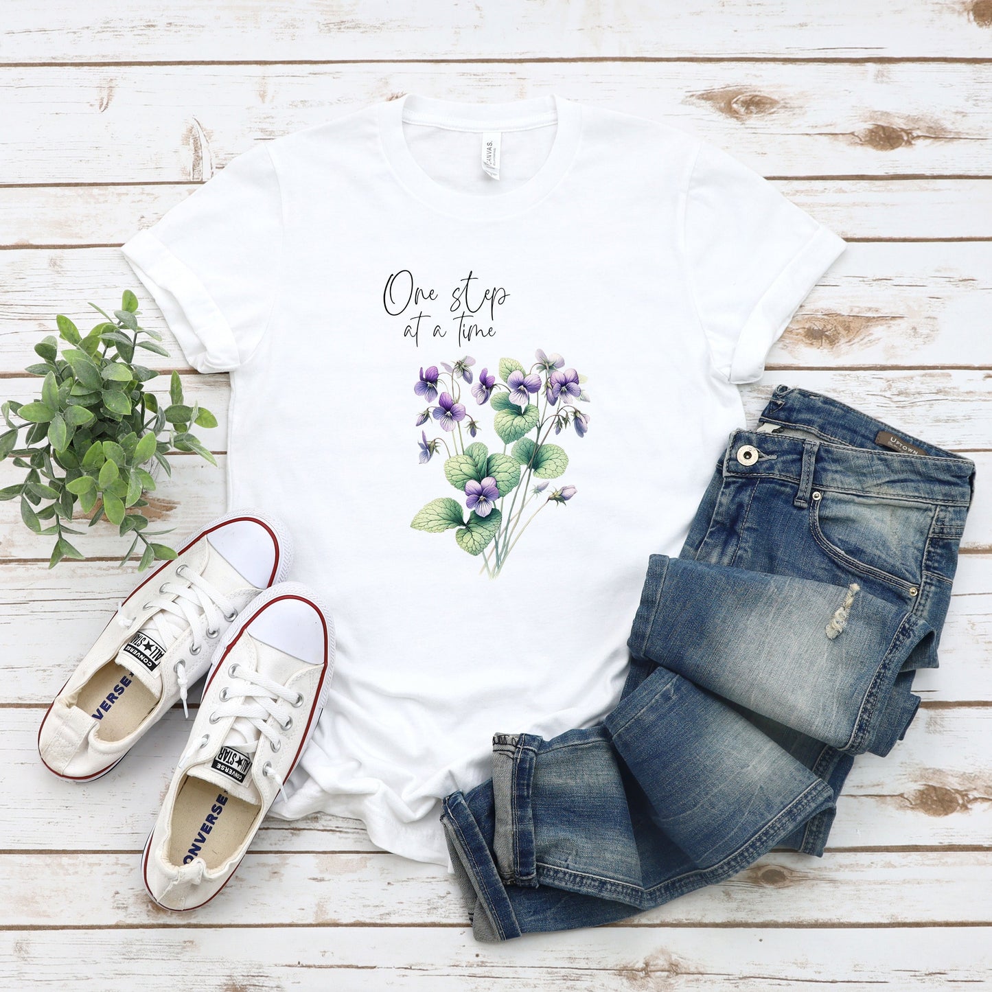 A t-shirt featuring a beautiful violet for February with the quote “One step at a time.” Perfect for February birthdays and floral art lovers. Comfortable and stylish for casual outings or celebrations. Bella+Canvas 3001 t-shirt in white. ReadyShirtAim.com