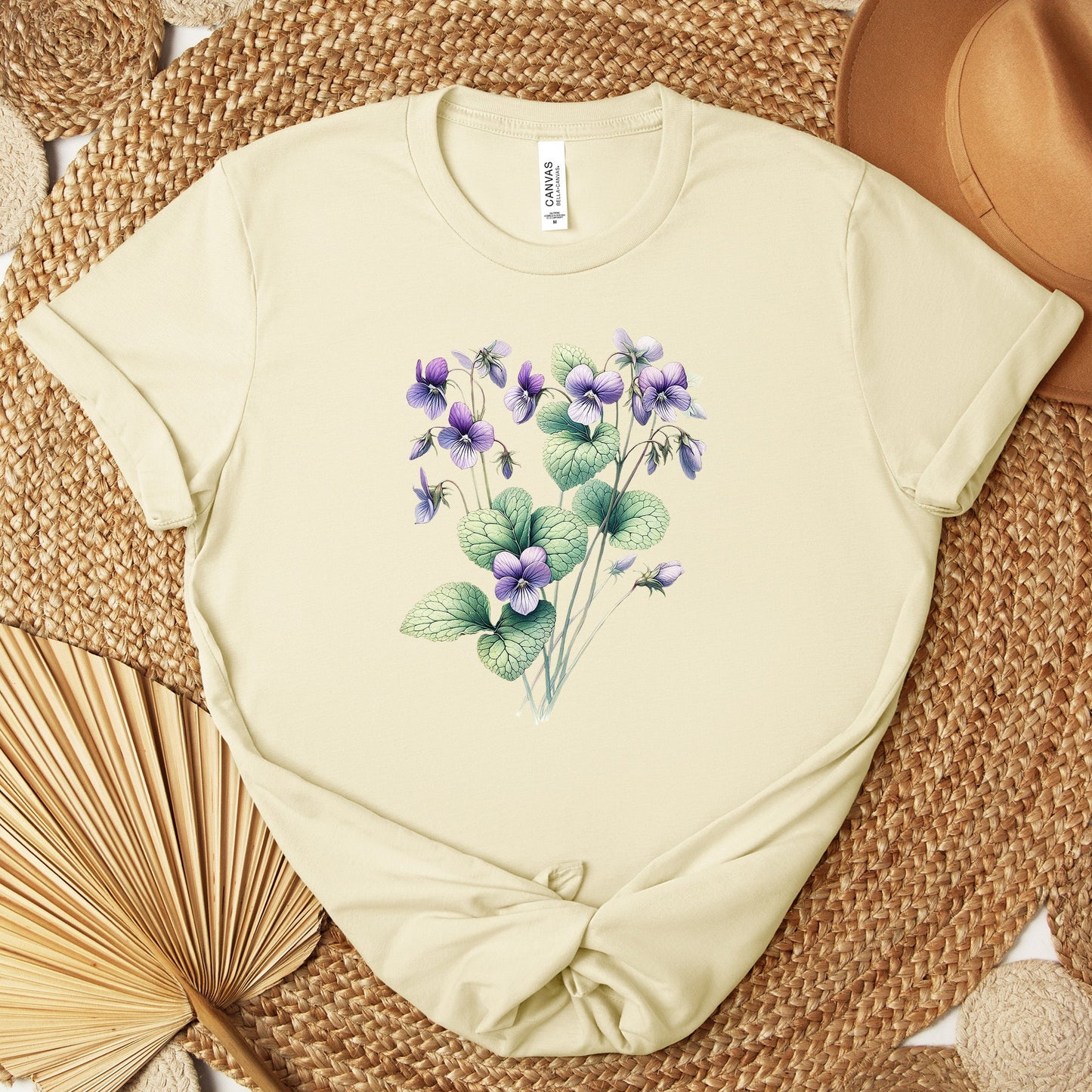 A t-shirt featuring a beautiful violet for February. Perfect for February birthdays and floral art lovers. Comfortable and stylish for casual outings or celebrations. Bella+Canvas 3001 t-shirt in natural. ReadyShirtAim.com