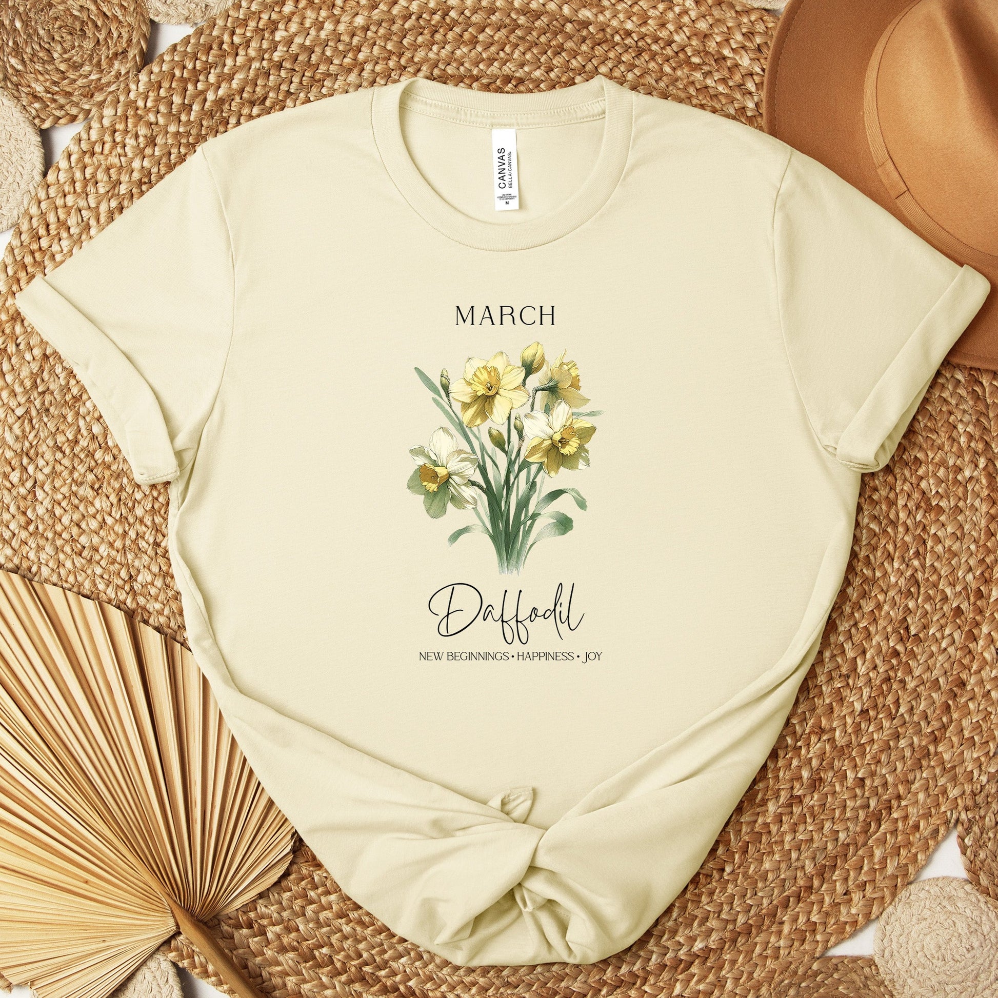 A t-shirt featuring a beautiful daffodil for March with traits New Beginnings, Happiness, Joy. Perfect for March birthdays and floral art lovers. Comfortable and stylish for casual outings or celebrations. Bella+Canvas 3001 t-shirt in natural. ReadyShirtAim.com