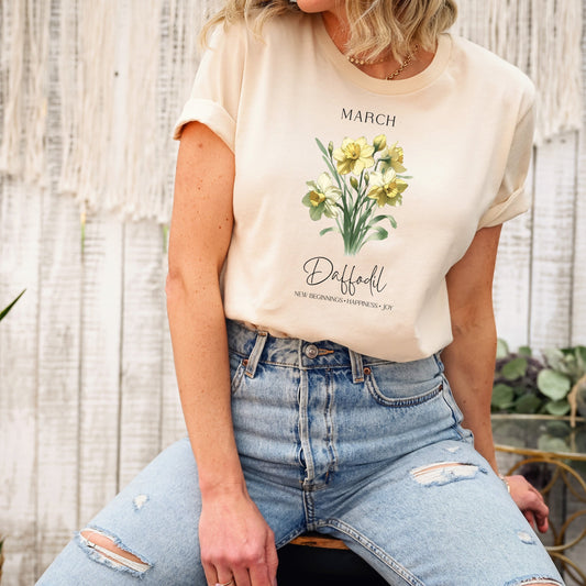 A t-shirt featuring a beautiful daffodil for March with traits New Beginnings, Happiness, Joy. Perfect for March birthdays and floral art lovers. Comfortable and stylish for casual outings or celebrations. Bella+Canvas 3001 t-shirt in soft cream. ReadyShirtAim.com