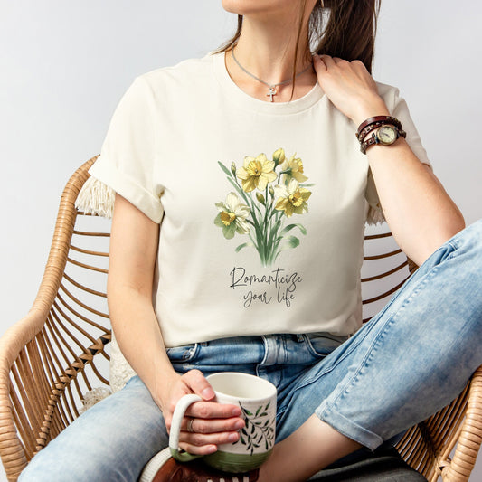 A t-shirt featuring a beautiful daffodil for March with the quote “Romanticize your life.” Perfect for March birthdays and floral art lovers. Comfortable and stylish for casual outings or celebrations. Bella+Canvas 3001 t-shirt in natural. ReadyShirtAim.com