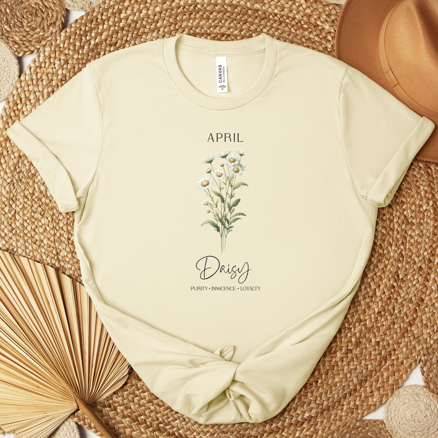 A t-shirt featuring a beautiful daisy for April with traits Purity, Innocence, Loyalty. Perfect for April birthdays and floral art lovers. Comfortable and stylish for casual outings or celebrations. Bella+Canvas 3001 t-shirt in natural. ReadyShirtAim.com