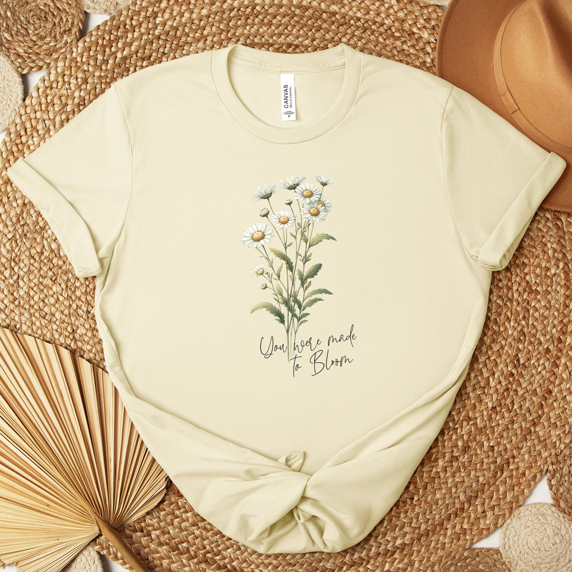 A t-shirt featuring a beautiful daisy for April with the quote “You were made to bloom.” Perfect for April birthdays and floral art lovers. Comfortable and stylish for casual outings or celebrations. Bella+Canvas 3001 t-shirt in natural. ReadyShirtAim.com