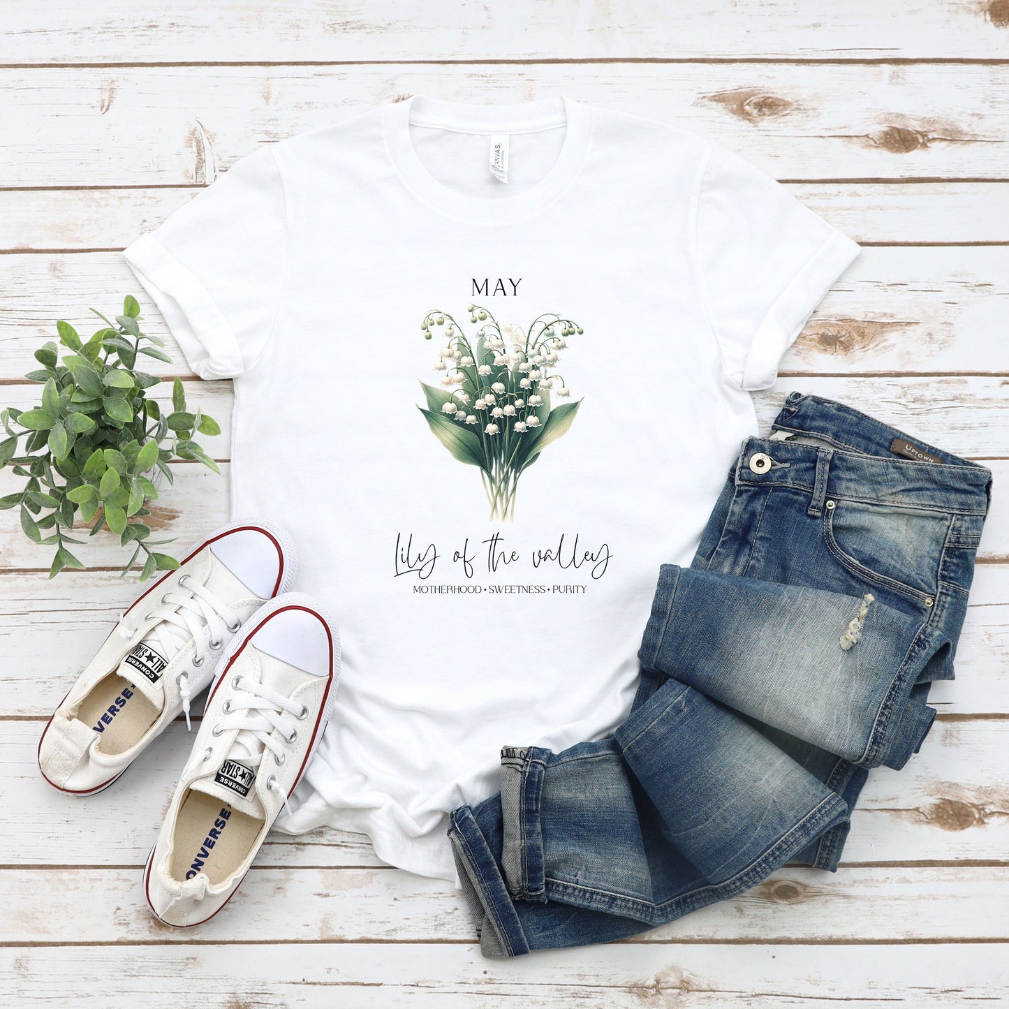 A t-shirt featuring a beautiful Lily of the Valley for May with traits Motherhood, Sweetness, Purity. Perfect for May birthdays and floral art lovers. Comfortable and stylish for casual outings or celebrations. Bella+Canvas 3001 t-shirt in white. ReadyShirtAim.com