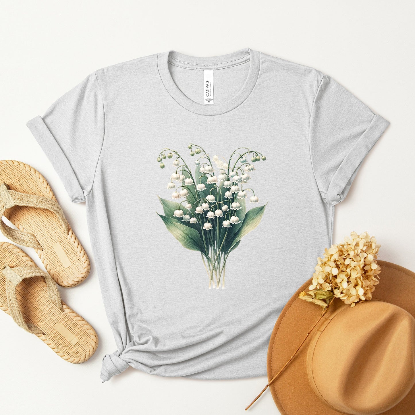 A t-shirt featuring a beautiful Lily of the Valley for May. Perfect for May birthdays and floral art lovers. Comfortable and stylish for casual outings or celebrations. Bella+Canvas 3001 t-shirt in ash. ReadyShirtAim.com