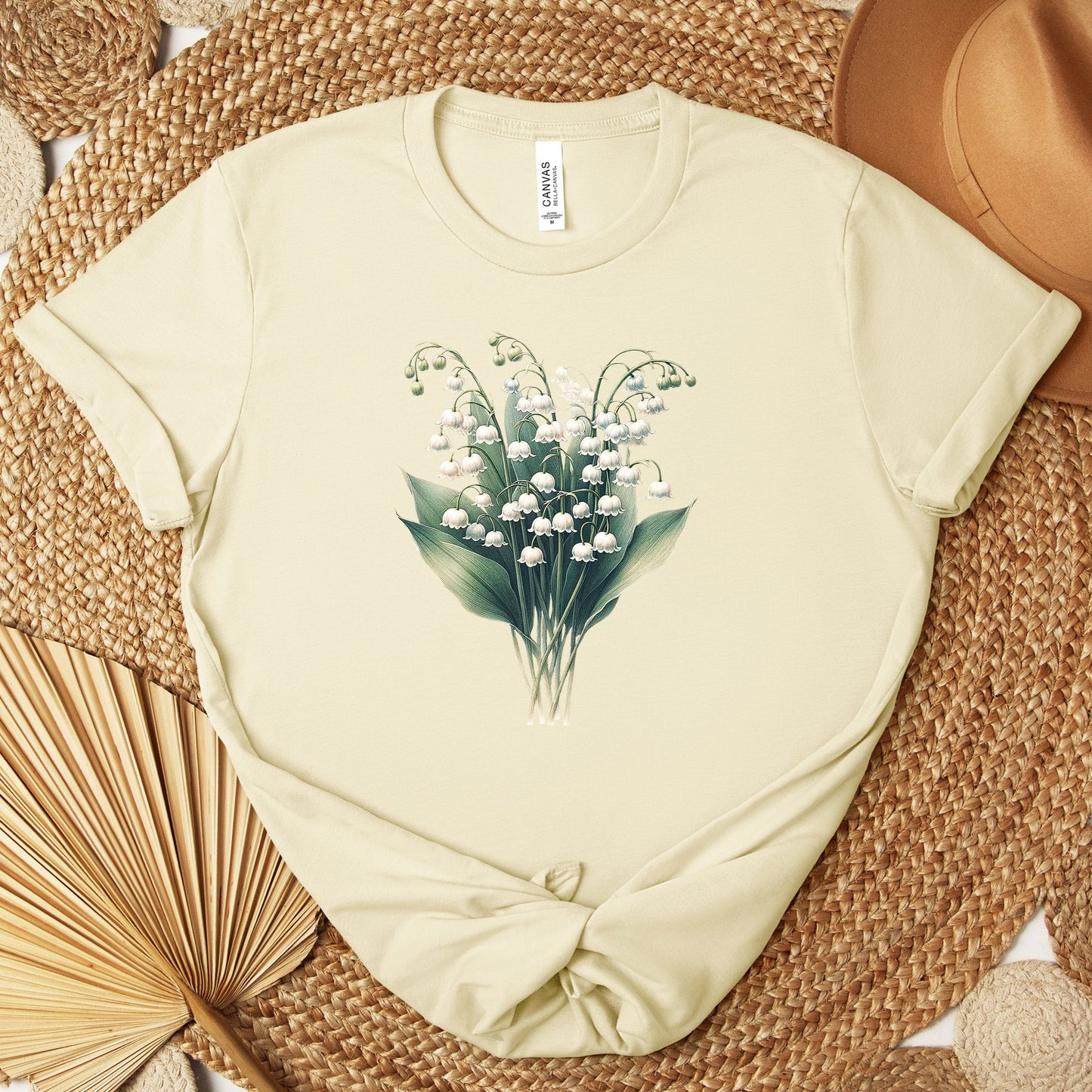 A t-shirt featuring a beautiful Lily of the Valley for May. Perfect for May birthdays and floral art lovers. Comfortable and stylish for casual outings or celebrations. Bella+Canvas 3001 t-shirt in natural. ReadyShirtAim.com