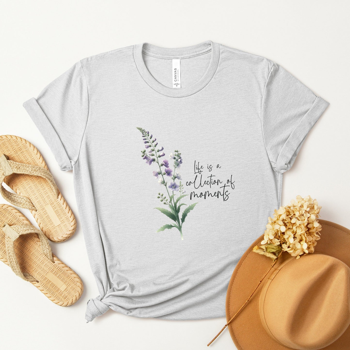 A t-shirt featuring a beautiful larkspur for July with the quote “Life is a collection of moments.” Perfect for July birthdays and floral art lovers. Comfortable and stylish for casual outings or celebrations. Bella+Canvas 3001 t-shirt in ash. ReadyShirtAim.com