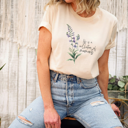 A t-shirt featuring a beautiful larkspur for July with the quote “Life is a collection of moments.” Perfect for July birthdays and floral art lovers. Comfortable and stylish for casual outings or celebrations. Bella+Canvas 3001 t-shirt in soft cream. ReadyShirtAim.com