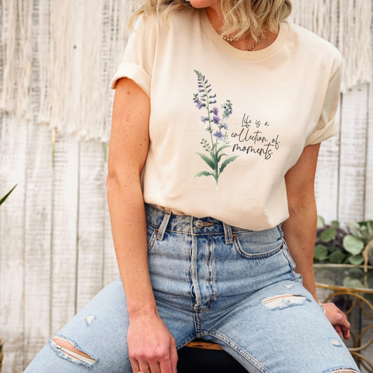 A t-shirt featuring a beautiful larkspur for July with the quote “Life is a collection of moments.” Perfect for July birthdays and floral art lovers. Comfortable and stylish for casual outings or celebrations. Bella+Canvas 3001 t-shirt in soft cream. ReadyShirtAim.com