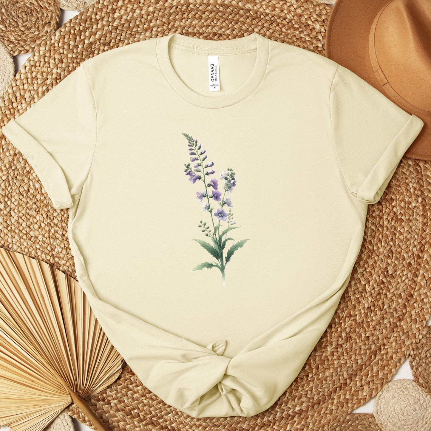 A t-shirt featuring a beautiful larkspur for July. Perfect for July birthdays and floral art lovers. Comfortable and stylish for casual outings or celebrations. Bella+Canvas 3001 t-shirt in natural. ReadyShirtAim.com