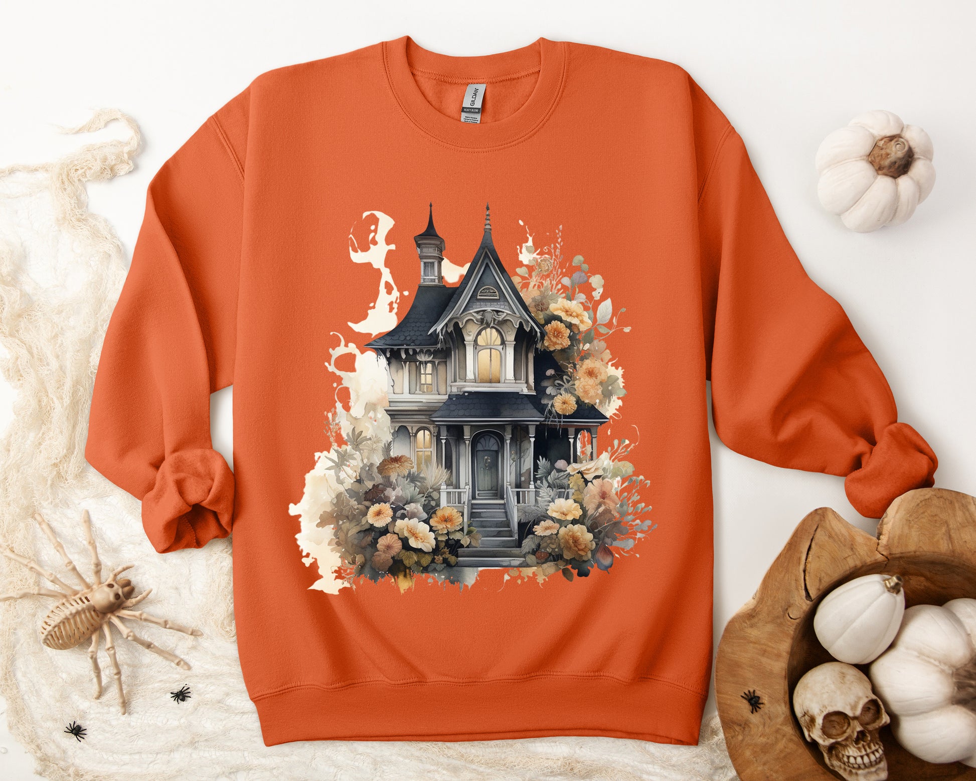 Halloween Boho Sweatshirt for Women featuring a haunted house illustration with boho design elements. Perfect for autumn festivities and casual wear. Available in multiple dark and light colors and sizes. Gildan 18000 sweatshirt in Orange. ReadyShirtAim.com