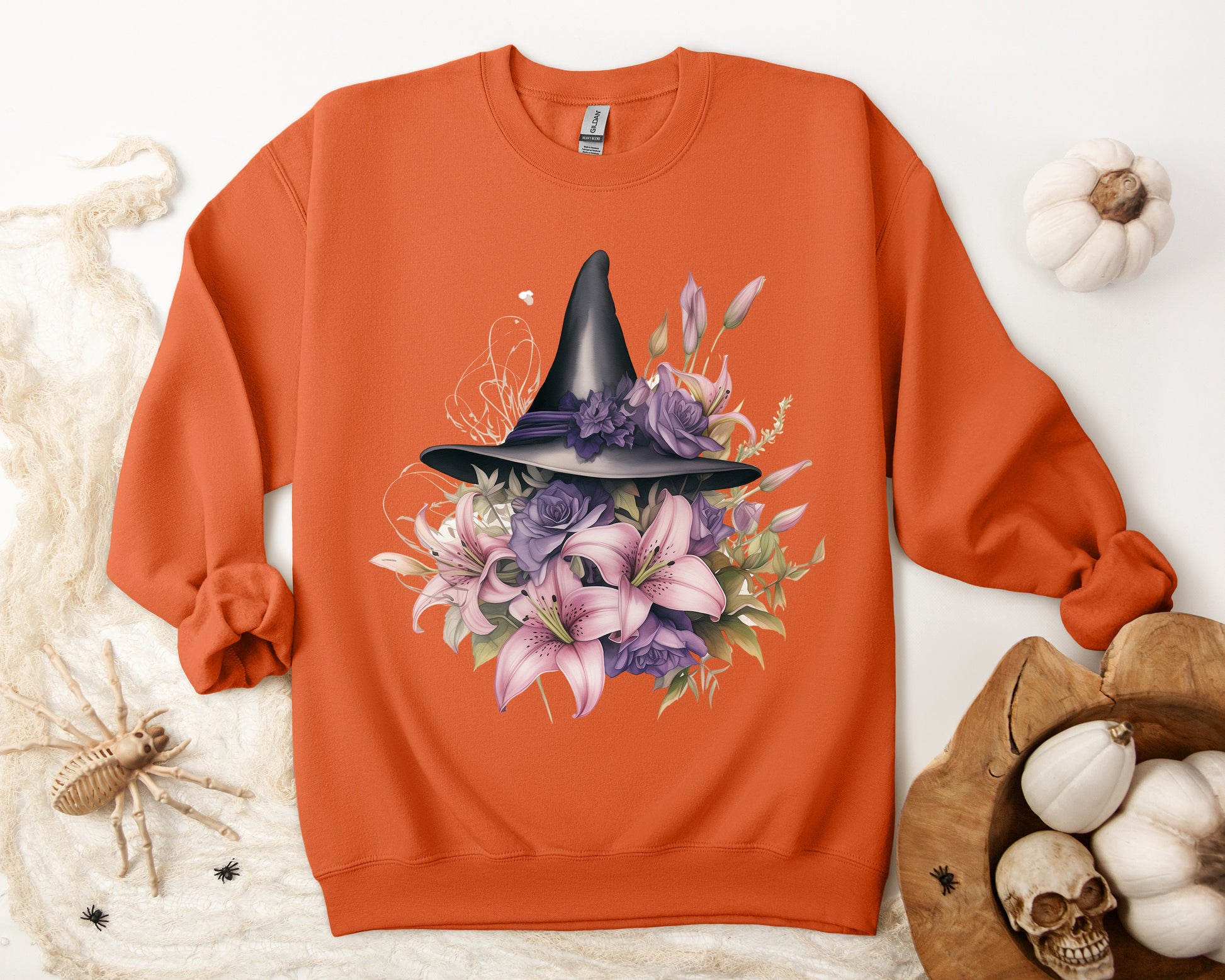 Enchanting Bohemian Witch Hat Sweatshirt with a watercolor illustration of a black witch hat surrounded by flowers in purple, pink, and green tones. Available in multiple dark ang light colors and sizes. Gildan 18000 sweatshirt in Orange. ReadyShirtAim.com