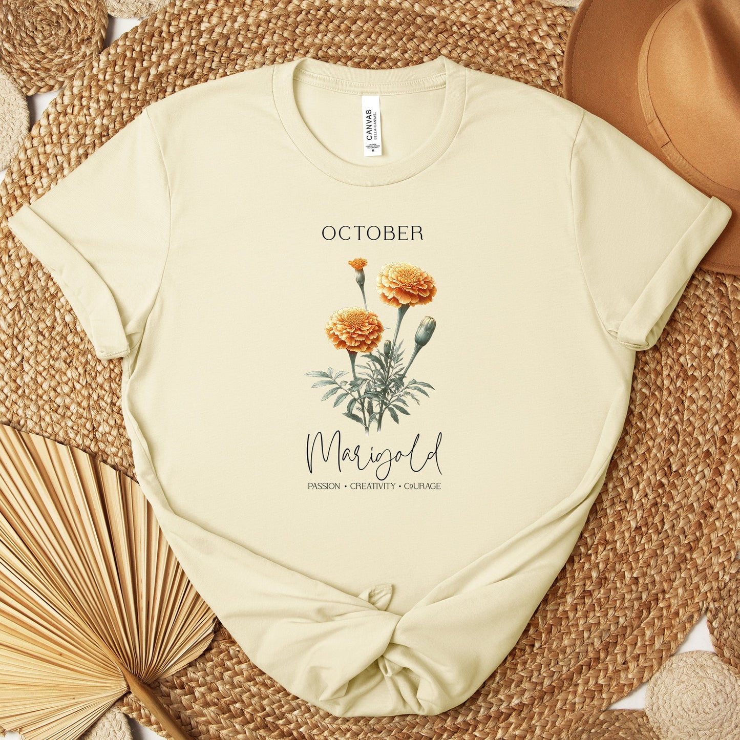 A t-shirt featuring a beautiful marigold for October with traits Passion, Creativity, Courage. Perfect for October birthdays and floral art lovers. Comfortable and stylish for casual outings or celebrations. Bella+Canvas 3001 t-shirt in natural. ReadyShirtAim.com