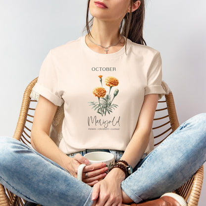 A t-shirt featuring a beautiful marigold for October with traits Passion, Creativity, Courage. Perfect for October birthdays and floral art lovers. Comfortable and stylish for casual outings or celebrations. Bella+Canvas 3001 t-shirt in soft cream. ReadyShirtAim.com