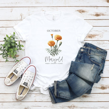 A t-shirt featuring a beautiful marigold for October with traits Passion, Creativity, Courage. Perfect for October birthdays and floral art lovers. Comfortable and stylish for casual outings or celebrations. Bella+Canvas 3001 t-shirt in white. ReadyShirtAim.com