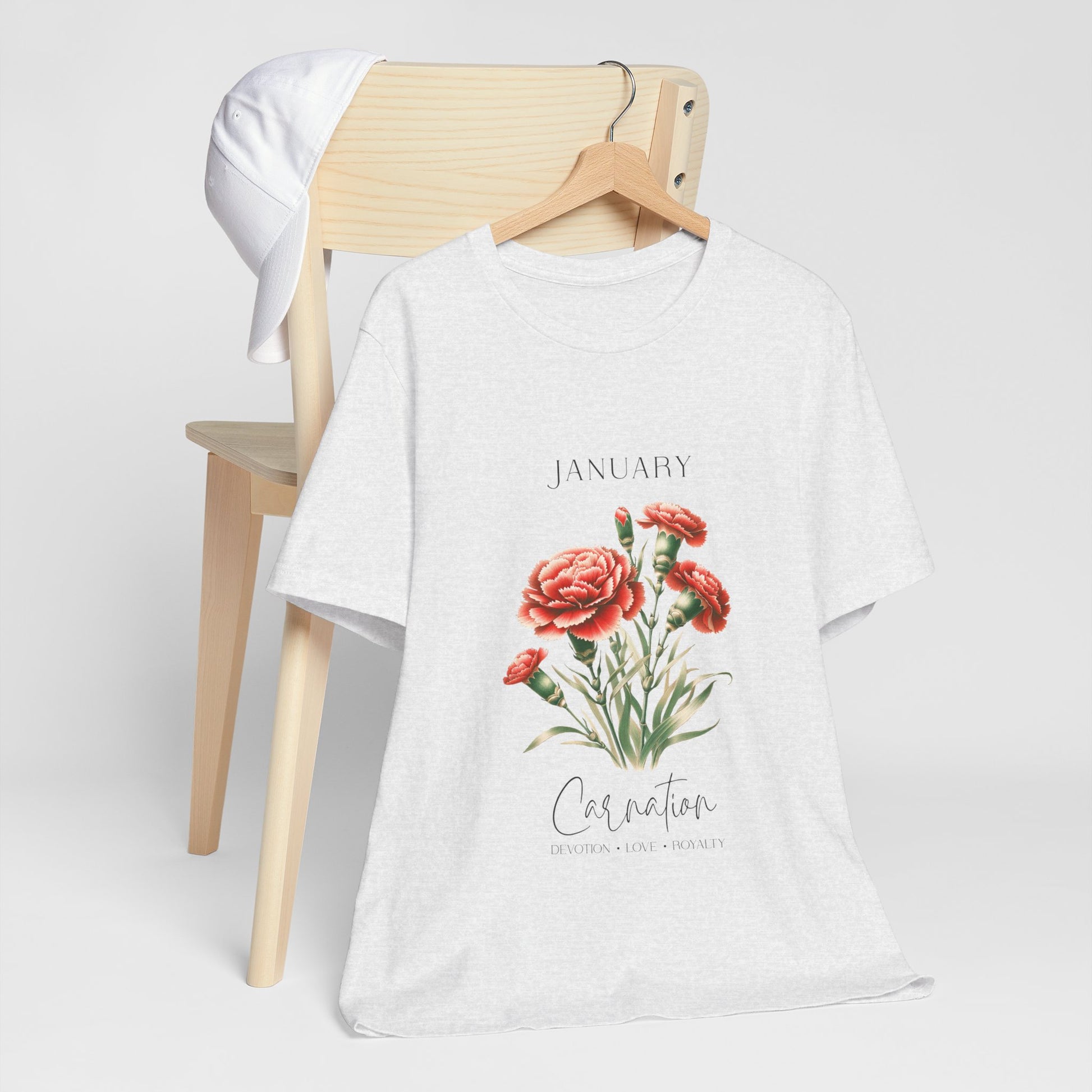 A t-shirt featuring a beautiful carnation for January with traits Devotion, Love, Loyalty. Perfect for January birthdays and floral art lovers. Comfortable and stylish for casual outings or celebrations. Bella+Canvas 3001 t-shirt in ash. ReadyShirtAim.com