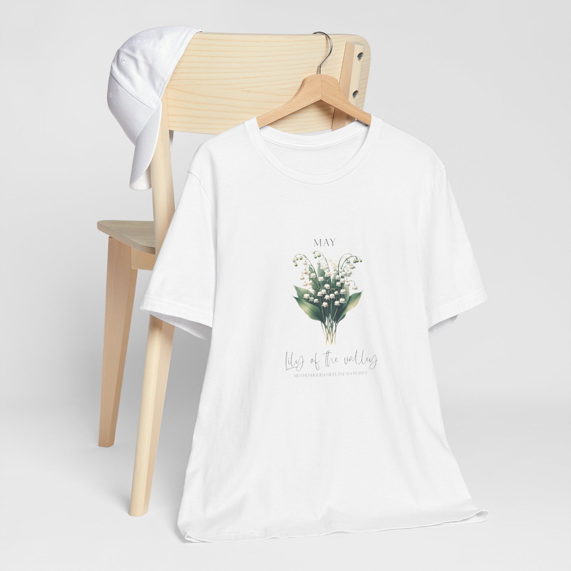 A t-shirt featuring a beautiful Lily of the Valley for May with traits Motherhood, Sweetness, Purity. Perfect for May birthdays and floral art lovers. Comfortable and stylish for casual outings or celebrations. Bella+Canvas 3001 t-shirt in white. ReadyShirtAim.com