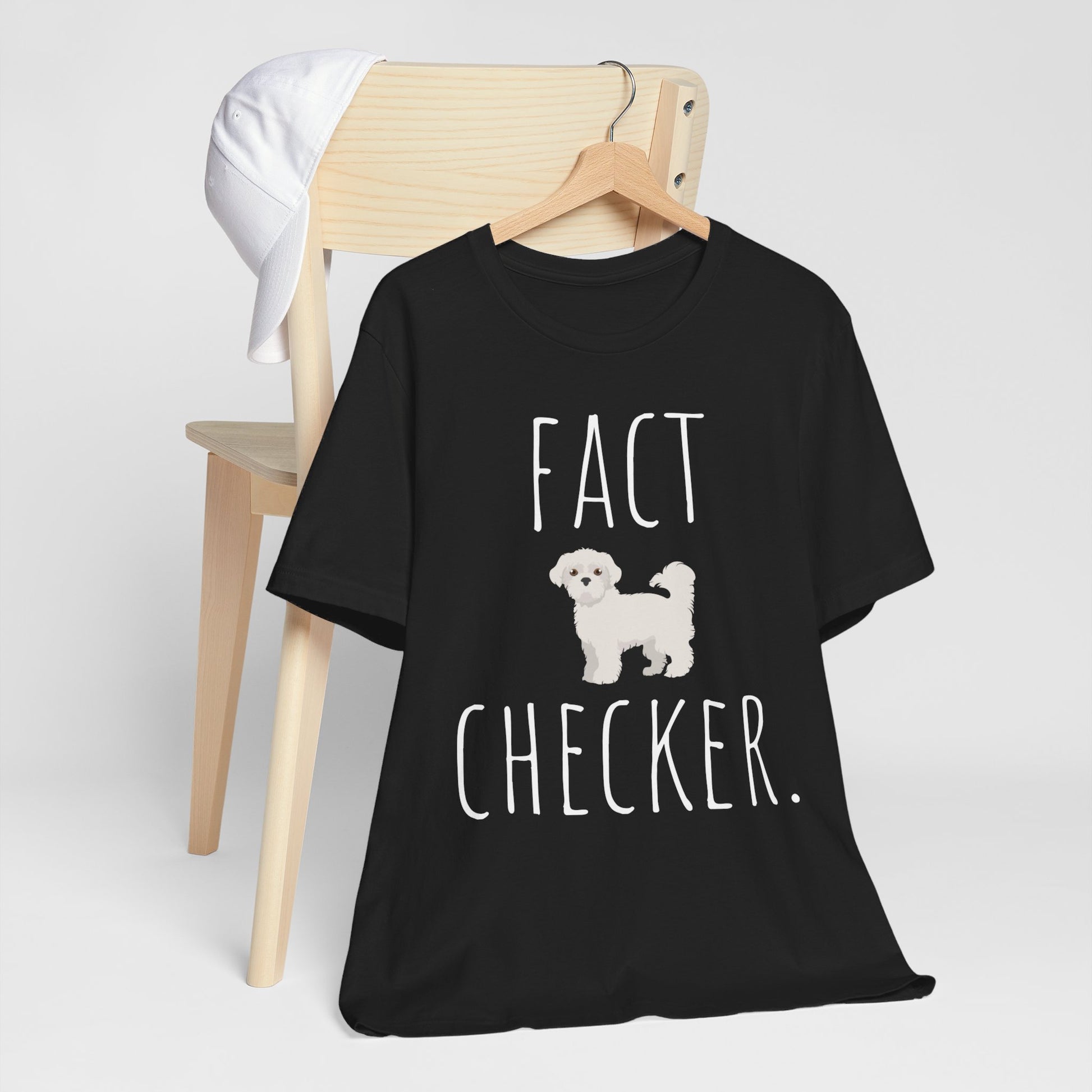 "Fact Checker" Maltese Dog T-Shirt for Unisex with a cute graphic of a Maltese dog and playful "Fact Checker" text underneath. Ideal for dog lovers. Ideal for dog lovers with a sense of humor. Available in multiple colors and sizes. Bella+Canvas 3001 t-shirt in black. ReadyShirtAim.com