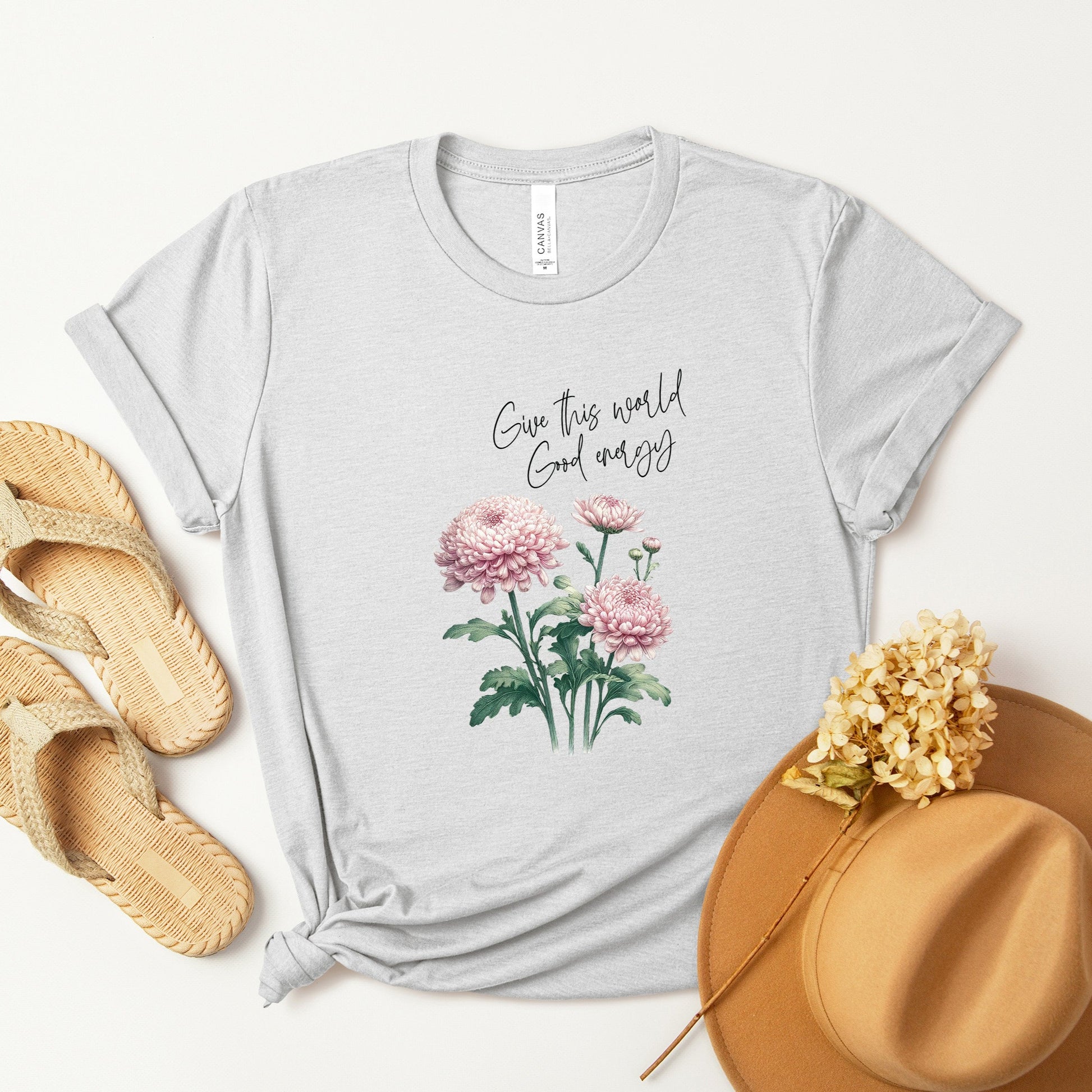 A t-shirt featuring a beautiful chrysanthemum for November with the quote “Give this world good energy.” Perfect for November birthdays and floral art lovers. Comfortable and stylish for casual outings or celebrations. Bella+Canvas 3001 t-shirt in ash. ReadyShirtAim.com