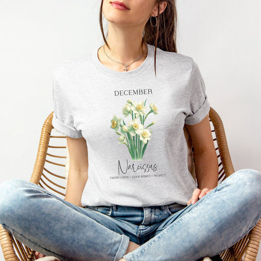 A t-shirt featuring a beautiful narcissus for December with traits Faithfulness, Good Wishes, Respect. Perfect for December birthdays and floral art lovers. Comfortable and stylish for casual outings or celebrations. Bella+Canvas 3001 t-shirt in ash. ReadyShirtAim.com