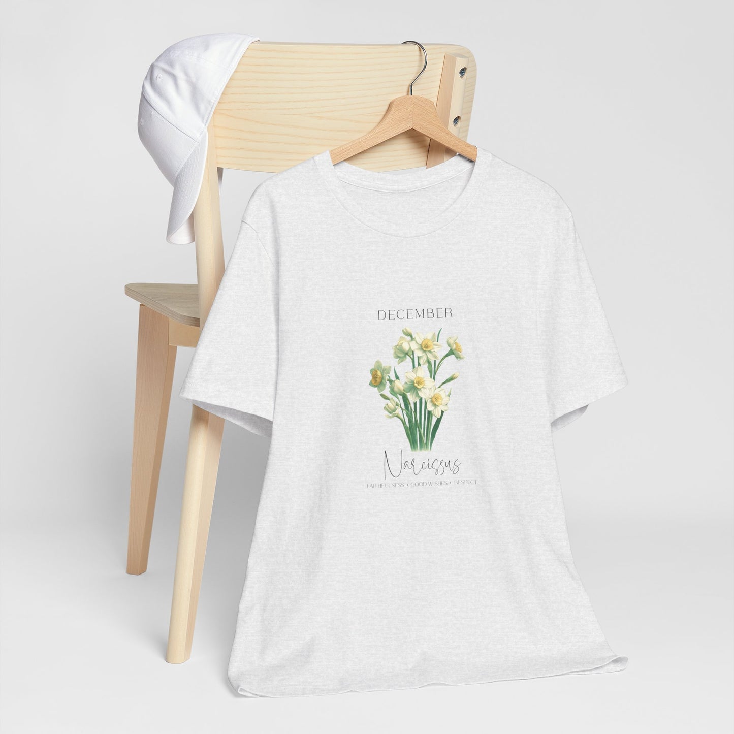 A t-shirt featuring a beautiful narcissus for December with traits Faithfulness, Good Wishes, Respect. Perfect for December birthdays and floral art lovers. Comfortable and stylish for casual outings or celebrations. Bella+Canvas 3001 t-shirt in ash. ReadyShirtAim.com