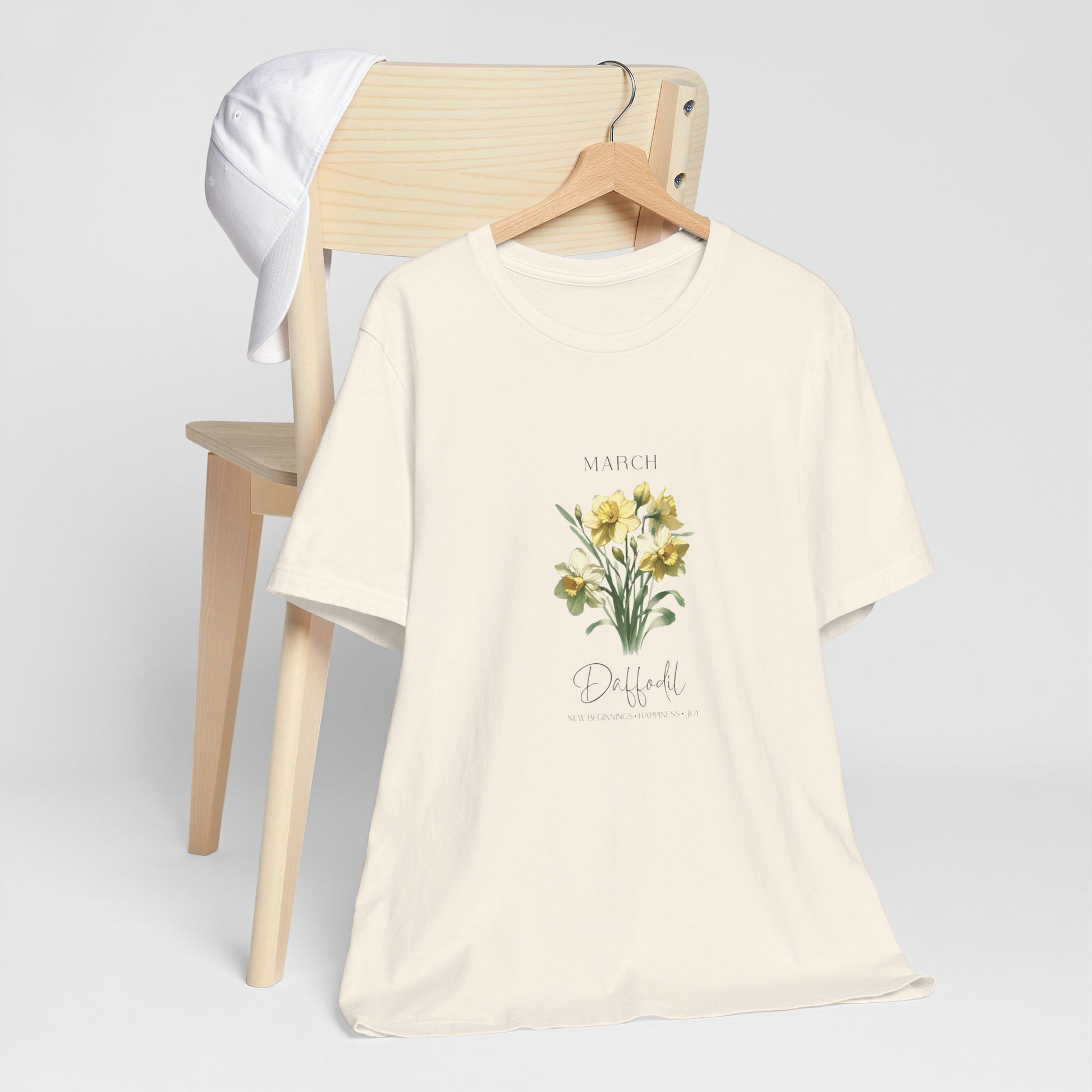 A t-shirt featuring a beautiful daffodil for March with traits New Beginnings, Happiness, Joy. Perfect for March birthdays and floral art lovers. Comfortable and stylish for casual outings or celebrations. Bella+Canvas 3001 t-shirt in natural. ReadyShirtAim.com