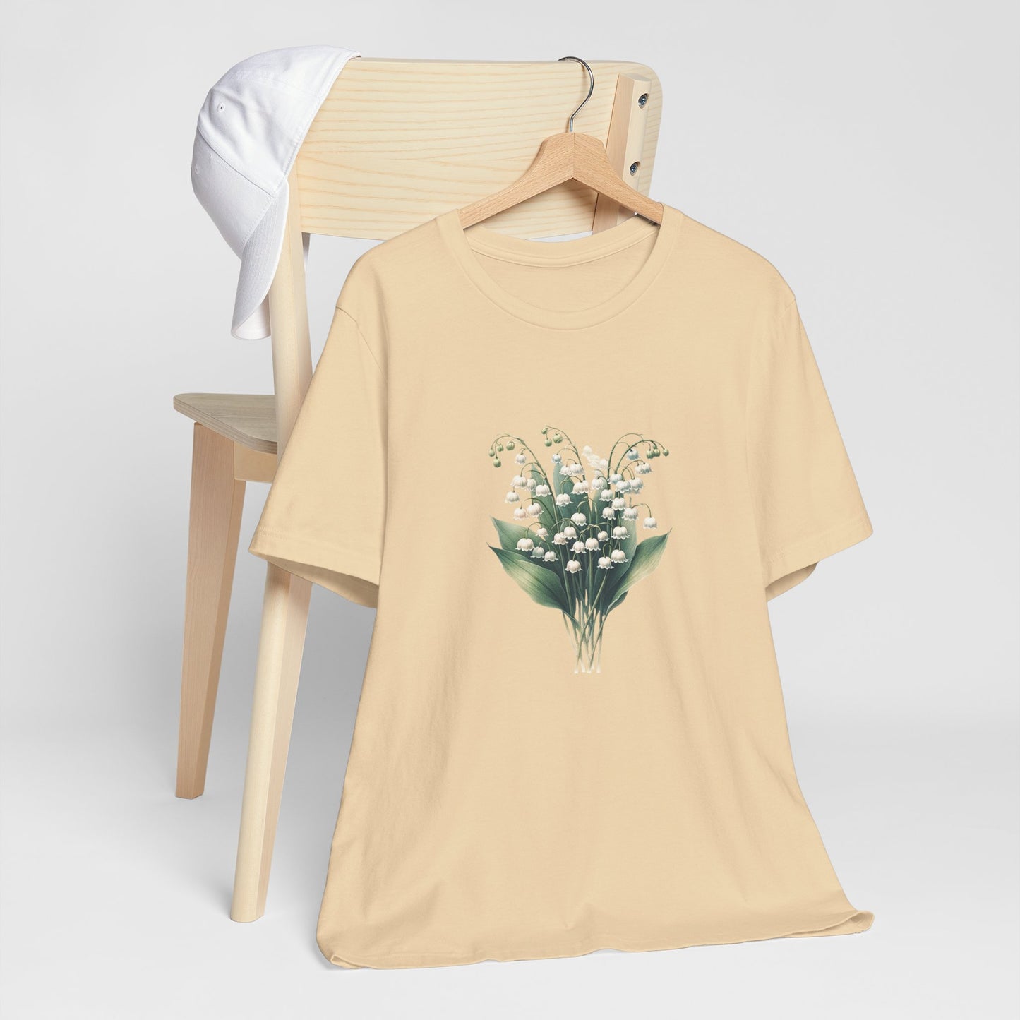 A t-shirt featuring a beautiful Lily of the Valley for May. Perfect for May birthdays and floral art lovers. Comfortable and stylish for casual outings or celebrations. Bella+Canvas 3001 t-shirt in soft cream. ReadyShirtAim.com