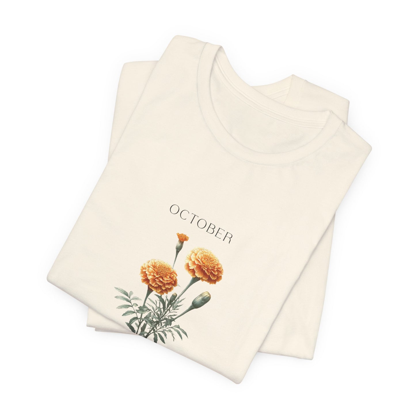 A t-shirt featuring a beautiful marigold for October with traits Passion, Creativity, Courage. Perfect for October birthdays and floral art lovers. Comfortable and stylish for casual outings or celebrations. Bella+Canvas 3001 t-shirt in natural. ReadyShirtAim.com