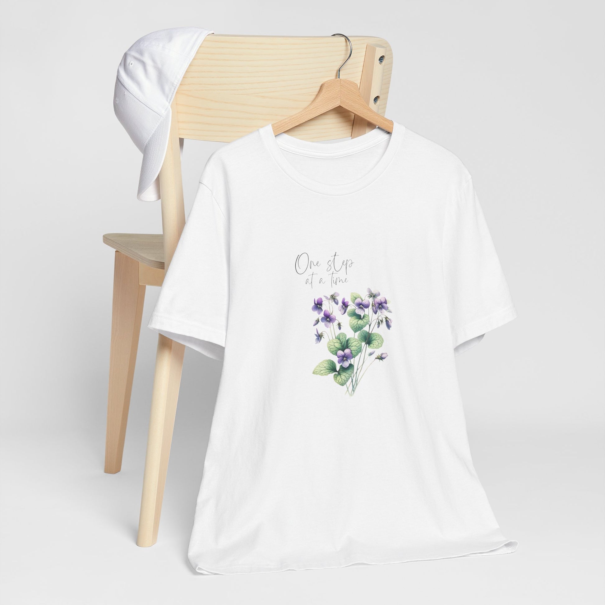 A t-shirt featuring a beautiful violet for February with the quote “One step at a time.” Perfect for February birthdays and floral art lovers. Comfortable and stylish for casual outings or celebrations. Bella+Canvas 3001 t-shirt in white. ReadyShirtAim.com