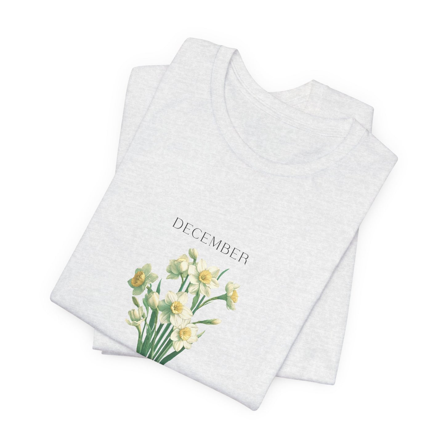 A t-shirt featuring a beautiful narcissus for December with traits Faithfulness, Good Wishes, Respect. Perfect for December birthdays and floral art lovers. Comfortable and stylish for casual outings or celebrations. Bella+Canvas 3001 t-shirt in ash. ReadyShirtAim.com