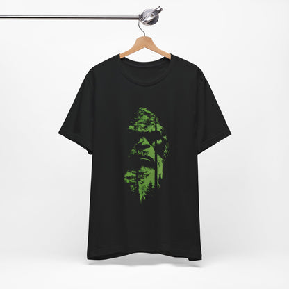 A t-shirt featuring an enigmatic cryptid design of Bigfoot's face, perfect for Bigfoot enthusiasts, cryptid fans, and adventure seekers. Comfortable and stylish for casual outings or cryptid conventions. Bella+Canvas 3001 t-shirt in black. ReadyShirtAim.com