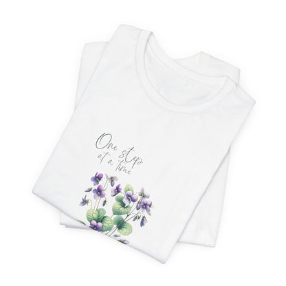 A t-shirt featuring a beautiful violet for February with the quote “One step at a time.” Perfect for February birthdays and floral art lovers. Comfortable and stylish for casual outings or celebrations. Bella+Canvas 3001 t-shirt in white. ReadyShirtAim.com