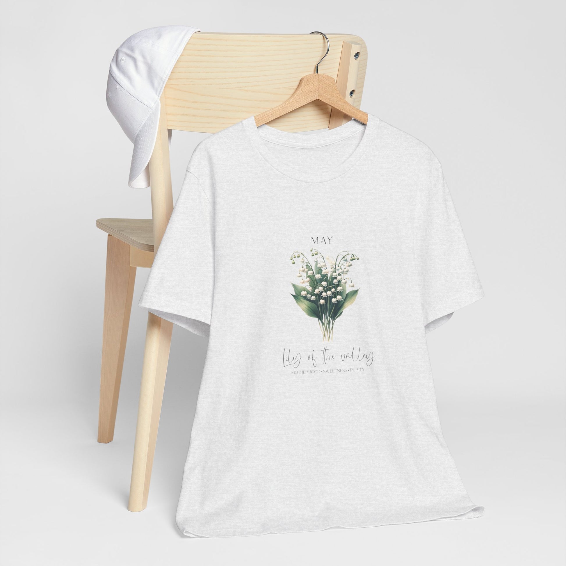 A t-shirt featuring a beautiful Lily of the Valley for May with traits Motherhood, Sweetness, Purity. Perfect for May birthdays and floral art lovers. Comfortable and stylish for casual outings or celebrations. Bella+Canvas 3001 t-shirt in ash. ReadyShirtAim.com