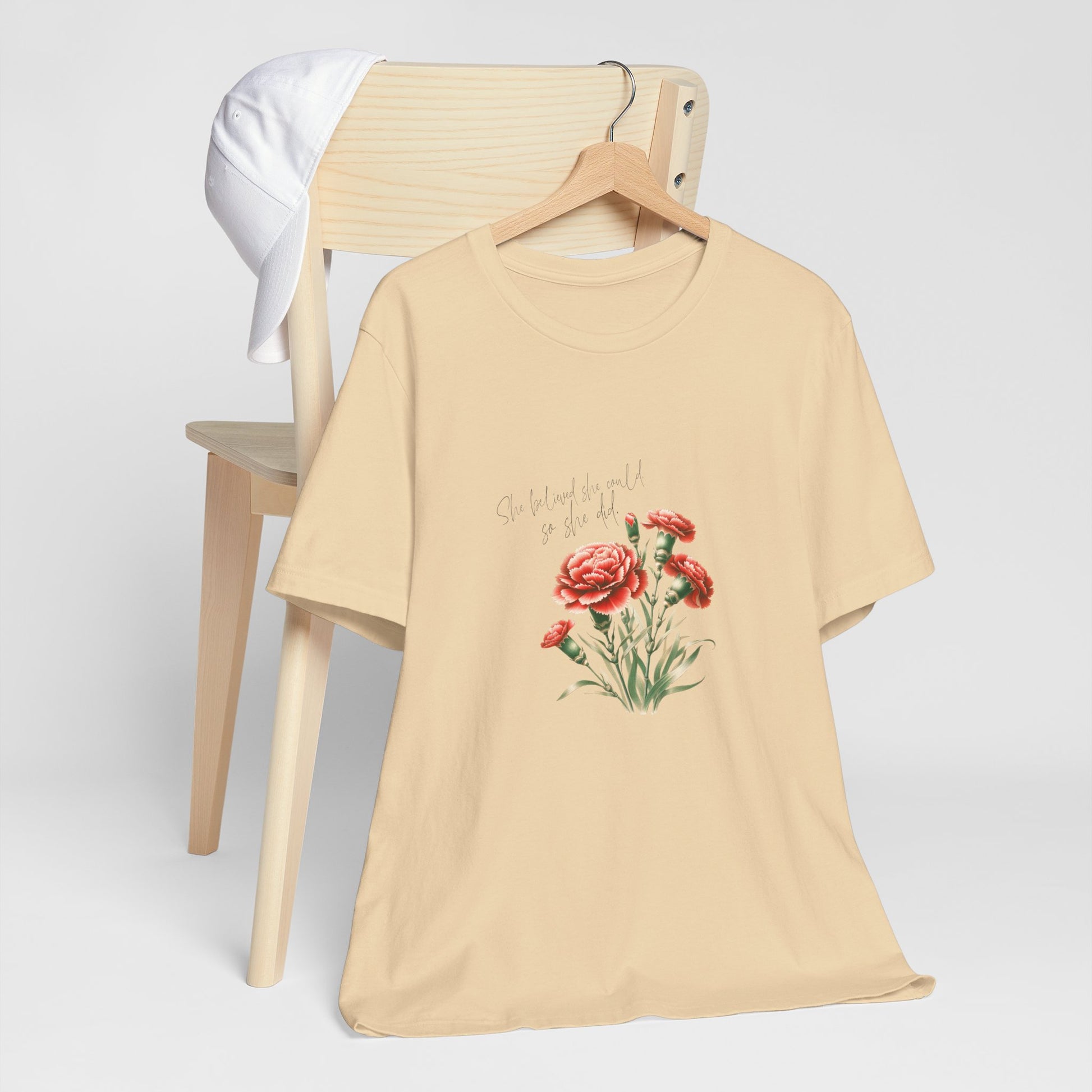 A t-shirt featuring a beautiful carnation for January with the quote “She believed she could, so she did.” Perfect for January birthdays and floral art lovers. Comfortable and stylish for casual outings or celebrations. Bella+Canvas 3001 t-shirt in soft cream. ReadyShirtAim.com