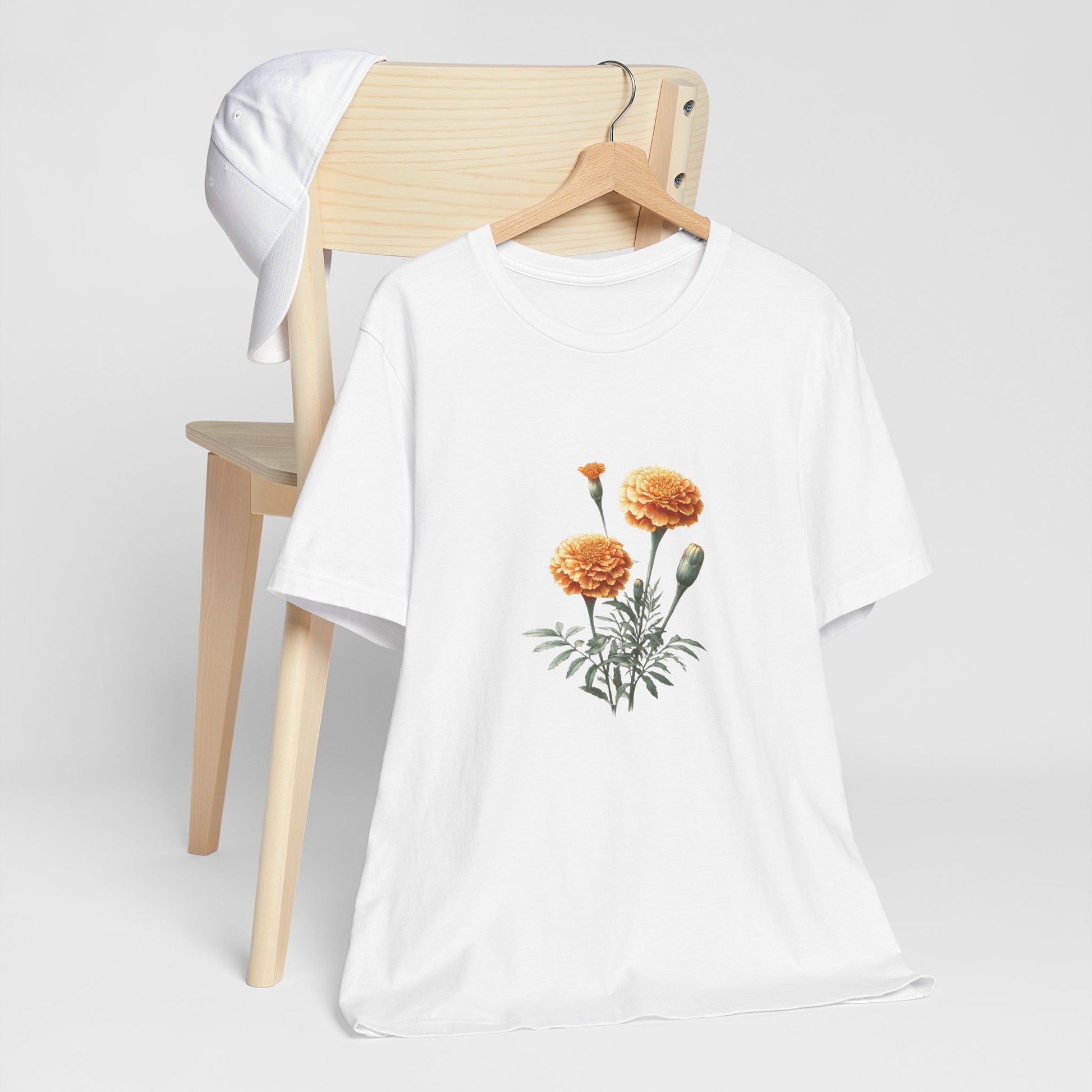 A t-shirt featuring a beautiful marigold for October. Perfect for October birthdays and floral art lovers. Comfortable and stylish for casual outings or celebrations. Bella+Canvas 3001 t-shirt in white. ReadyShirtAim.com