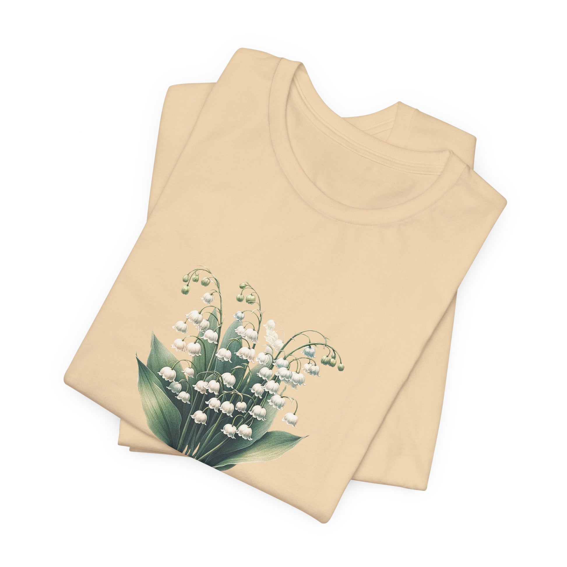 A t-shirt featuring a beautiful Lily of the Valley for May. Perfect for May birthdays and floral art lovers. Comfortable and stylish for casual outings or celebrations. Bella+Canvas 3001 t-shirt in soft cream. ReadyShirtAim.com