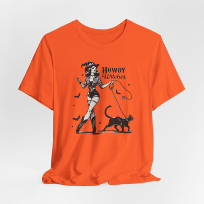 "Howdy Witches" Vintage 1950's Witch Halloween Women's T-Shirt featuring bold black text and a classic black-and-white image of a pin-up girl in sexy shorts and a western-style shirt, walking a black cat on a leash and smiling mischievously, perfect for adding a retro touch with playful Western charm to your Halloween festivities. Available in multiple colors and sizes.  Bella+Canvas 3001 t-shirt in orange. ReadyShirtAim.com