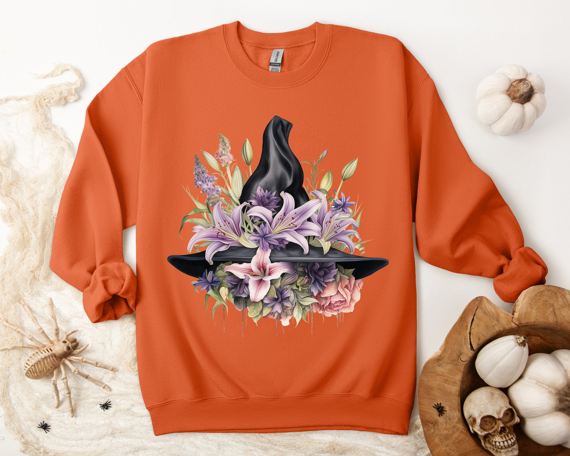 Mystical Floral Witch Hat Sweatshirt featuring a watercolor illustration of a black witch hat with flowers in purple, pink, and green. Available in multiple dark and light colors and sizes. Gildan 18000 sweatshirt in Orange. ReadyShirtAim.com