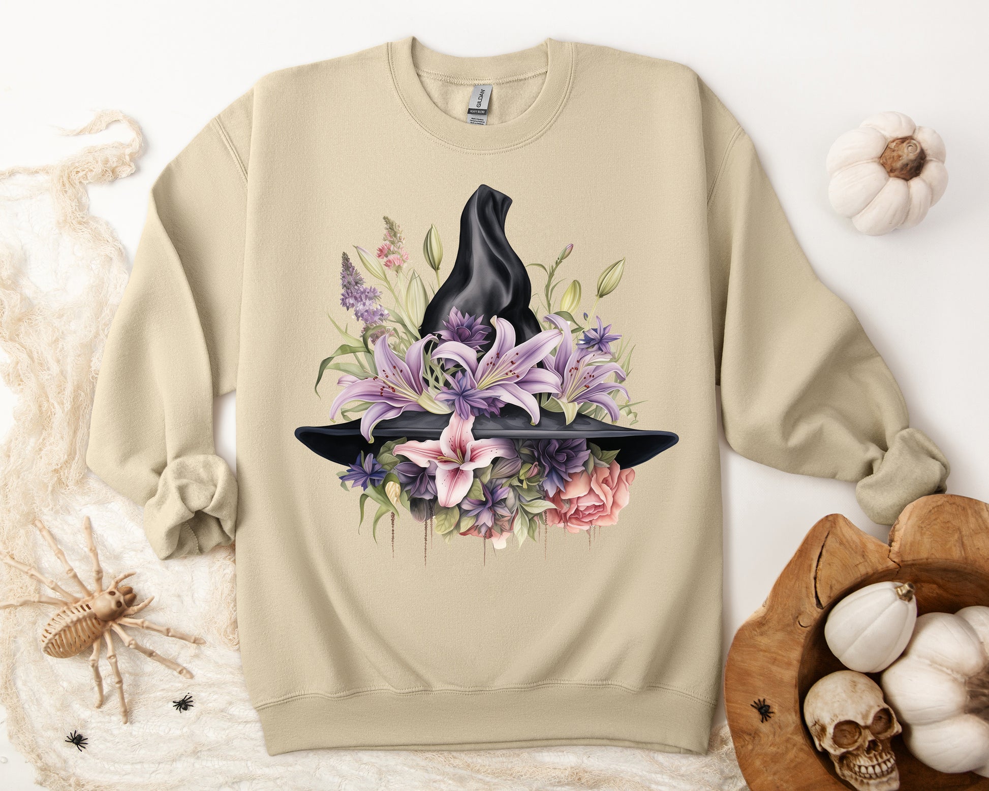 Mystical Floral Witch Hat Sweatshirt featuring a watercolor illustration of a black witch hat with flowers in purple, pink, and green. Available in multiple dark and light colors and sizes. Gildan 18000 sweatshirt in Sand. ReadyShirtAim.com