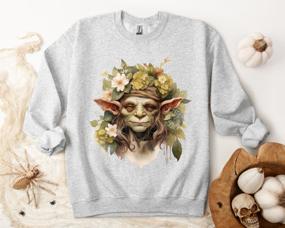 Creepy Cute Goblin Floral Boho Halloween Sweatshirt for women. Features a charming goblin surrounded by muted florals. Perfect for Halloween celebrations. Available in multiple dark and light colors and sizes. Gildan 18000 sweatshirt in ash. ReadyShirtAim.com