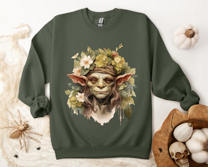 Creepy Cute Goblin Floral Boho Halloween Sweatshirt for women. Features a charming goblin surrounded by muted florals. Perfect for Halloween celebrations. Available in multiple dark and light colors and sizes. Gildan 18000 sweatshirt in Military Green. ReadyShirtAim.com