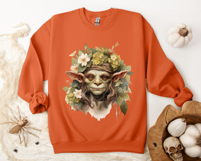 Creepy Cute Goblin Floral Boho Halloween Sweatshirt for women. Features a charming goblin surrounded by muted florals. Perfect for Halloween celebrations. Available in multiple dark and light colors and sizes. Gildan 18000 sweatshirt in Orange. ReadyShirtAim.com