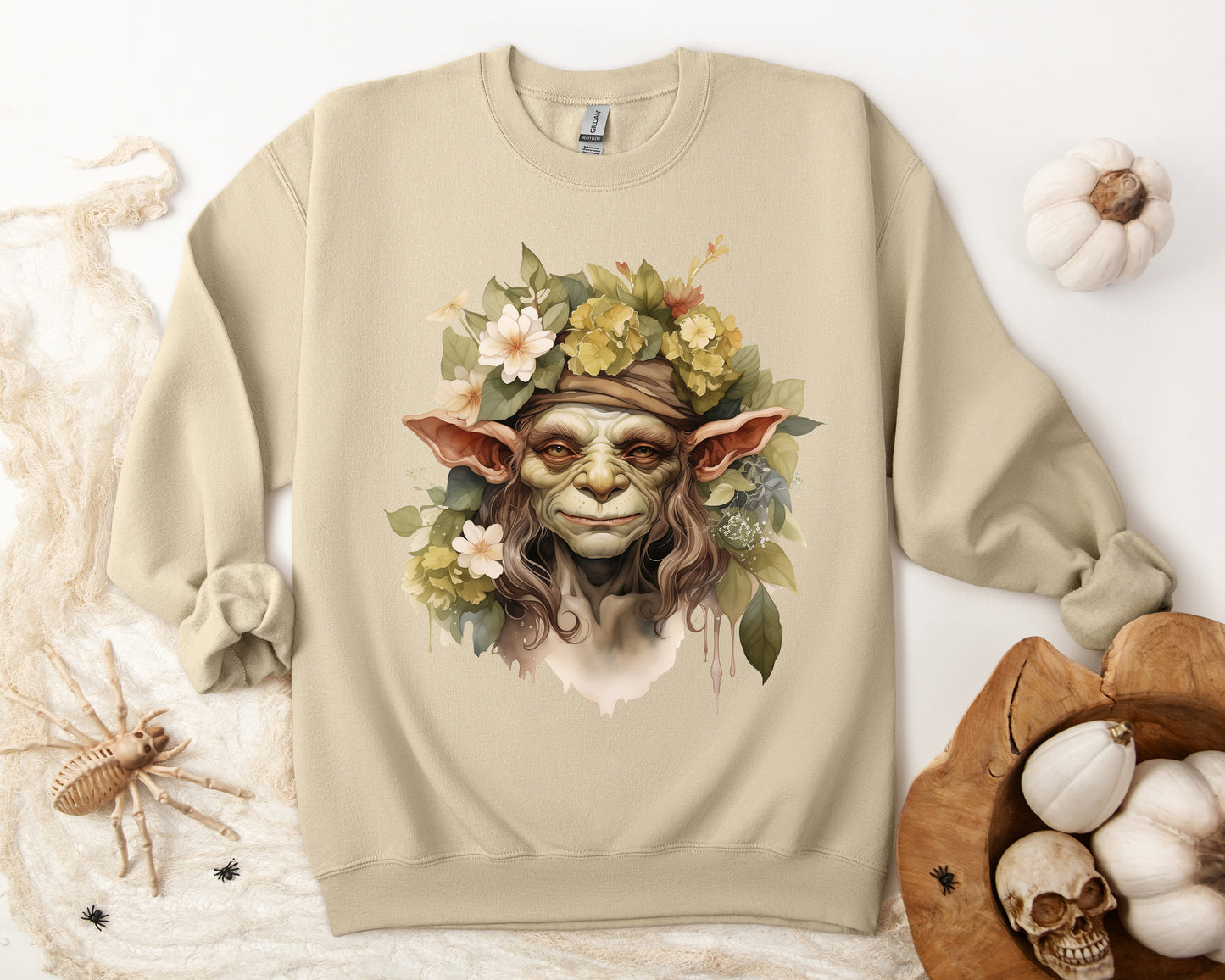 Creepy Cute Goblin Floral Boho Halloween Sweatshirt for women. Features a charming goblin surrounded by muted florals. Perfect for Halloween celebrations. Available in multiple dark and light colors and sizes. Gildan 18000 sweatshirt in Sand. ReadyShirtAim.com