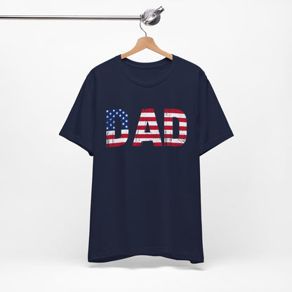 A dark t-shirt with bold "DAD" text filled with the American flag and a grunge texture. This patriotic shirt is perfect for Father's Day or any occasion to honor dad. Made from soft, breathable cotton for ultimate comfort. Available in multiple dark colors and sizes. Bella+Canvas 3001 t-shirt. ReadyShirtAim.com