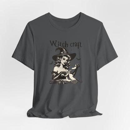 "Witch Craft" Vintage 1950's Witch Halloween Women's T-Shirt featuring bold black text and a classic black-and-white image of a pin-up girl in a sexy witch costume, focusing intently on crafting cut-out bats, perfect for adding a retro touch with crafty charm to your Halloween festivities. Available in multiple colors and sizes.  Bella+Canvas 3001 t-shirt in asphalt. ReadyShirtAim.com