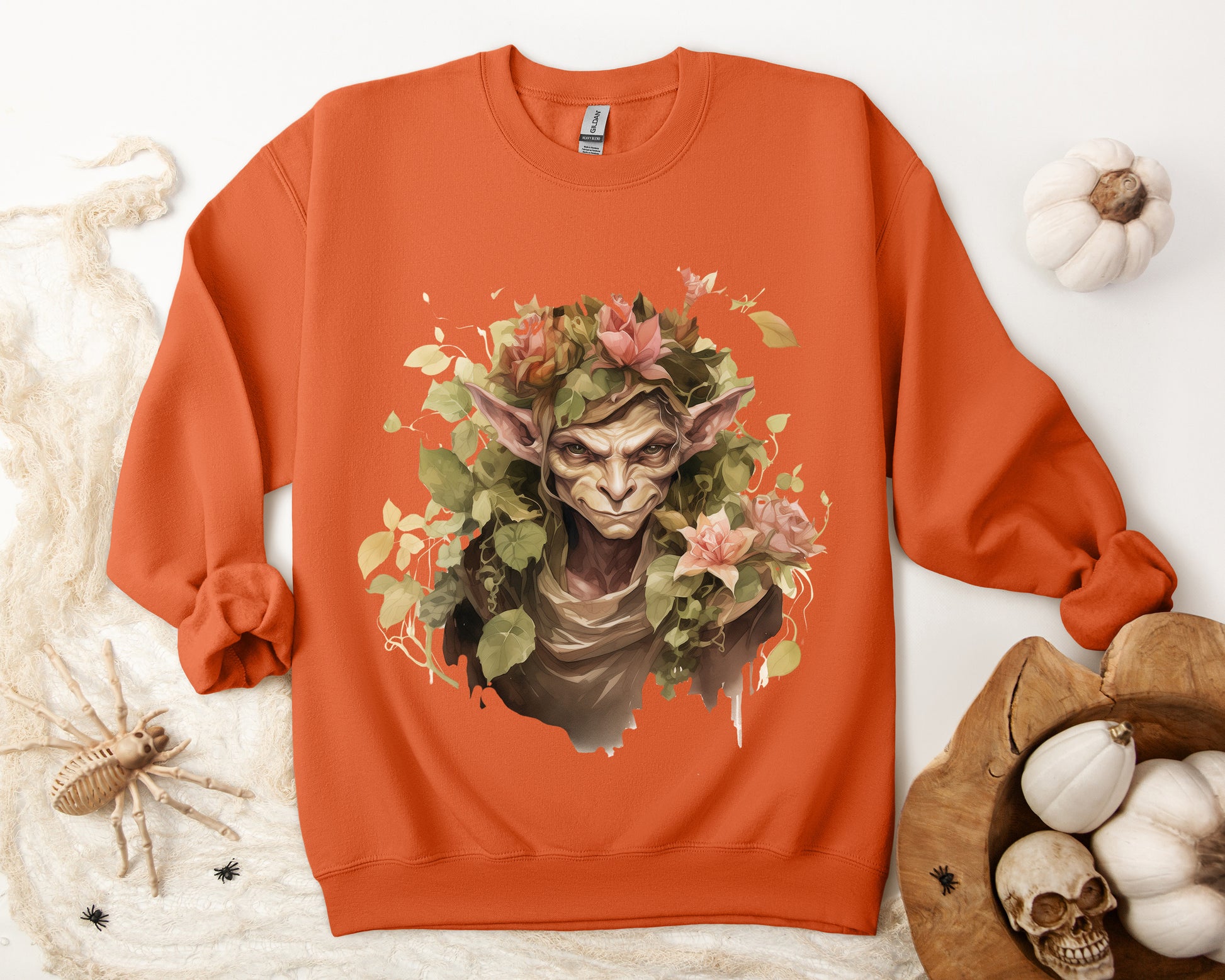 Boho Goblin Magic Halloween Sweatshirt for women. Features a charming goblin surrounded by muted florals. Perfect for Halloween celebrations. Available in multiple dark and light colors and sizes. Gildan 18000 sweatshirt in Orange. ReadyShirtAim.com