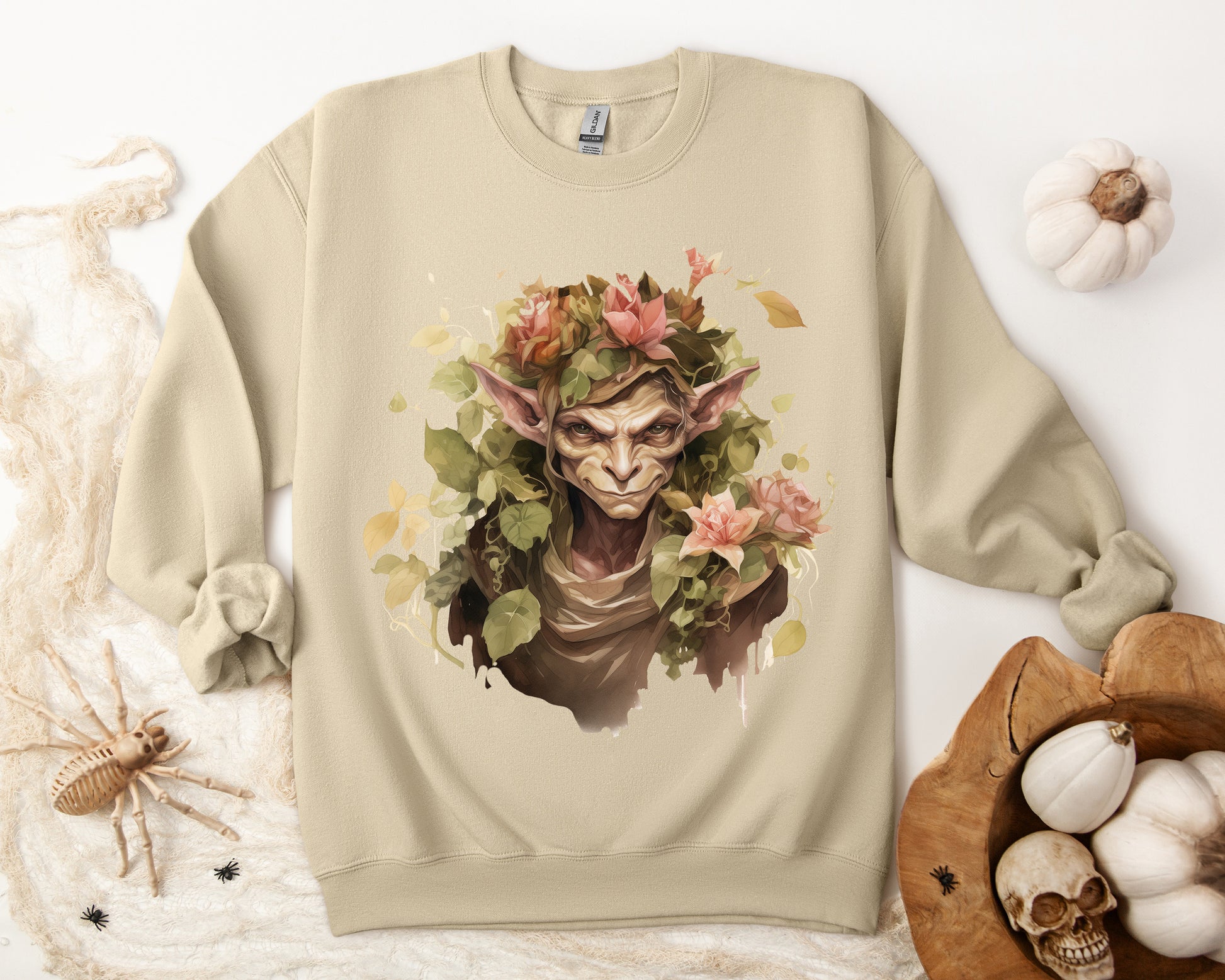 Boho Goblin Magic Halloween Sweatshirt for women. Features a charming goblin surrounded by muted florals. Perfect for Halloween celebrations. Available in multiple dark and light colors and sizes. Gildan 18000 sweatshirt in Sand. ReadyShirtAim.com