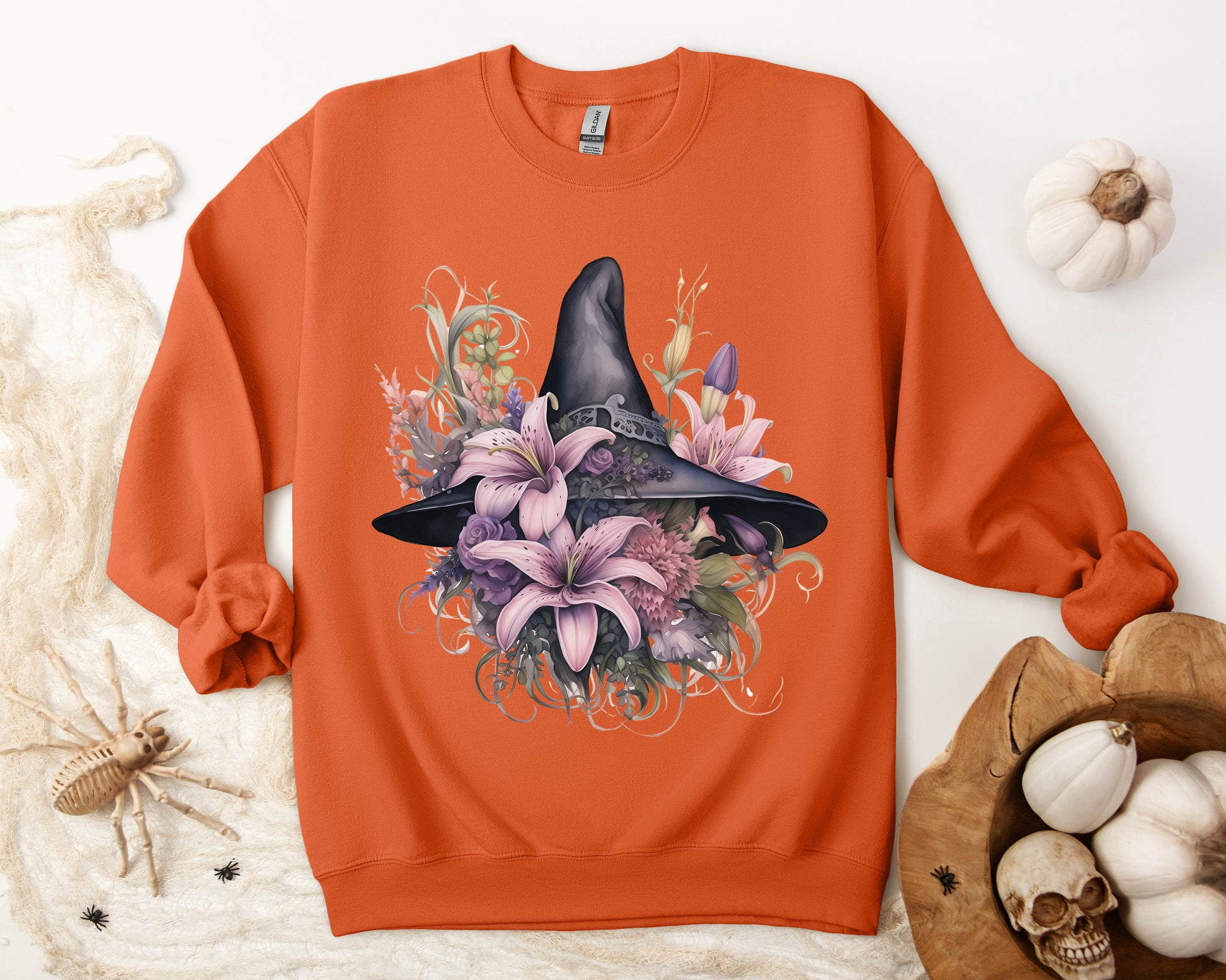 Charming Witch Hat & Flowers Sweatshirt with a watercolor illustration of a black witch hat and flowers in purple, pink, and green. Available in multiple dark and light colors and sizes. Gildan 18000 sweatshirt in Orange. ReadyShirtAim.com