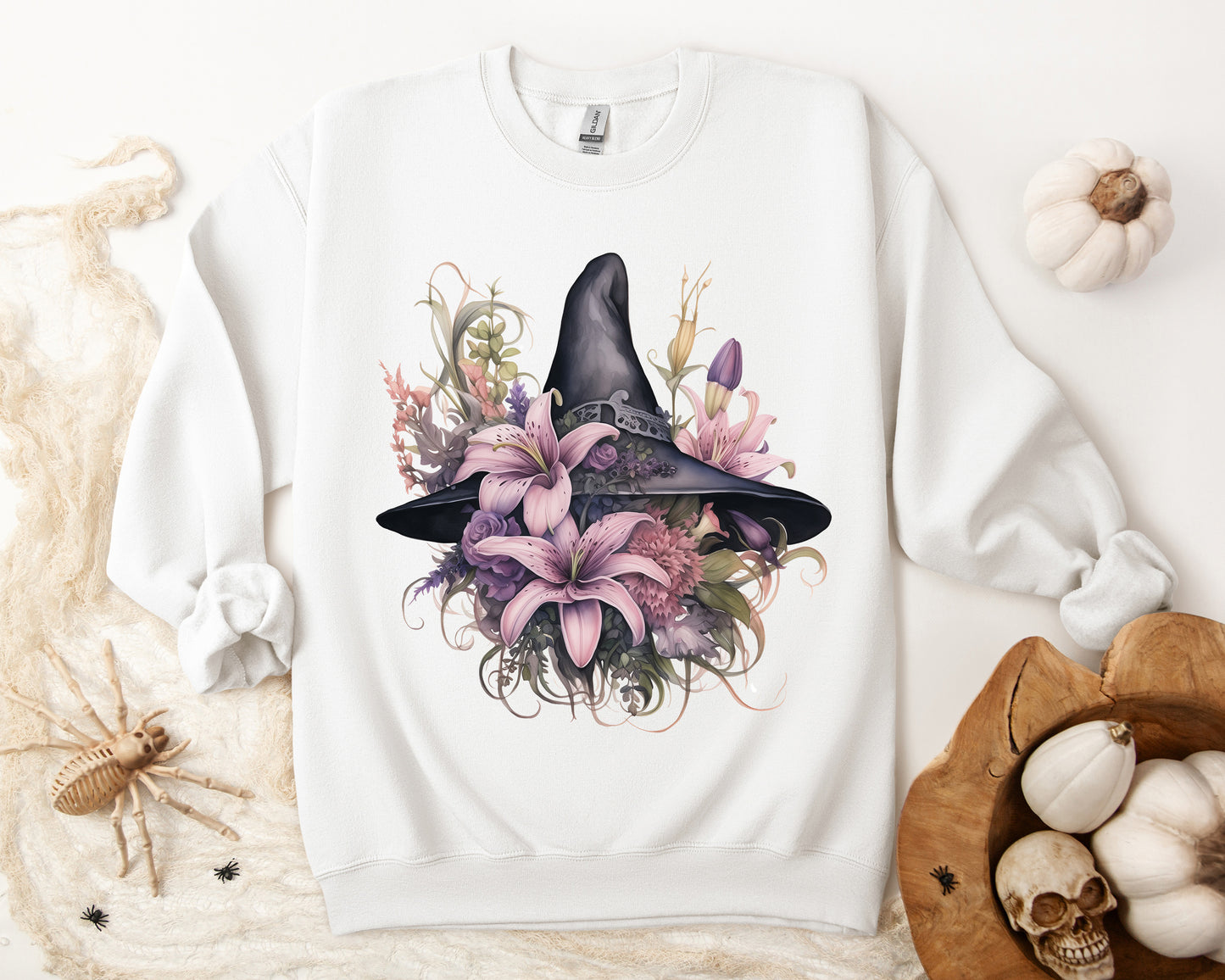 Charming Witch Hat & Flowers Sweatshirt with a watercolor illustration of a black witch hat and flowers in purple, pink, and green. Available in multiple dark and light colors and sizes. Gildan 18000 sweatshirt in white. ReadyShirtAim.com