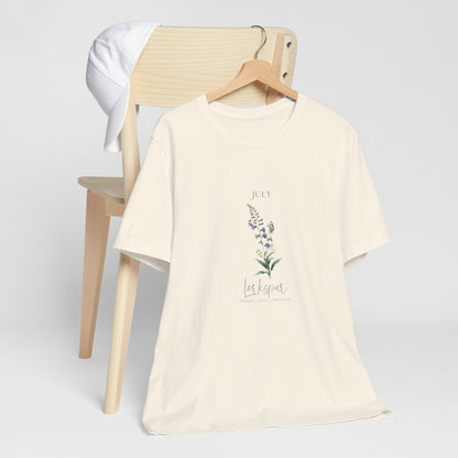 A t-shirt featuring a beautiful larkspur for July with traits Positive, Grace, First Love. Perfect for July birthdays and floral art lovers. Comfortable and stylish for casual outings or celebrations. Bella+Canvas 3001 t-shirt in natural. ReadyShirtAim.com